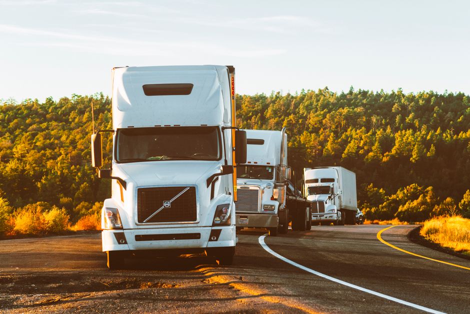 Truck accident attorney federal-liability context: a large commercial 18-wheeler tractor-trailer traveling down a multi-lane interstate highway under a clear sky, the standard interstate commerce profile that triggers federal motor carrier safety regulations and the $750,000 to $5 million liability minimums every truck accident attorney builds a commercial claim against