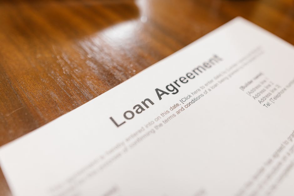 FHA loan requirements paperwork in detail: a close-up of a loan agreement document on a wooden table, the kind of file underwriters use to verify every line of the FHA loan requirements before clearing a borrower to close