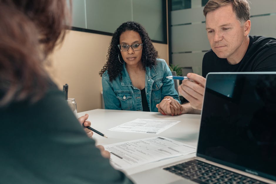 HELOC rates today comparison at the kitchen table: a homeowner couple reviewing mortgage paperwork and a laptop with rate sheets open, the practical sit-down where comparing HELOC rates today across four lenders translates directly into 1.5 to 2.5 percentage points of margin savings on the same underlying credit line
