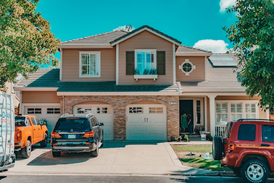 FHA loan requirements illustrated: a charming suburban house with a paved driveway and parked cars on a sunny day, the typical entry-level home FHA loan requirements were designed to make affordable for first-time buyers